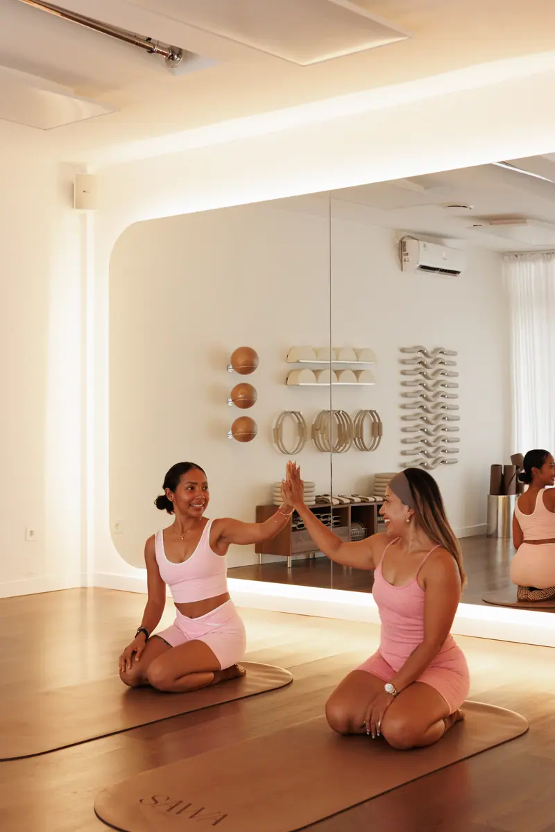 Two women sharing a high five on their mats at SAWA Studio in Kuta Lombok.